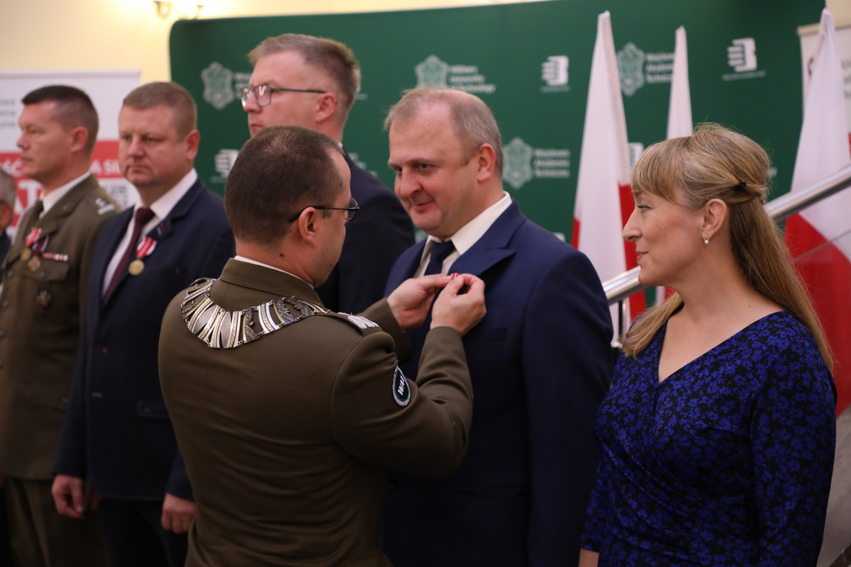 Fot. 3. Rektor-Komendant przypina odznaczenie do klapy marynarki Grzegorza Sławińskiego.