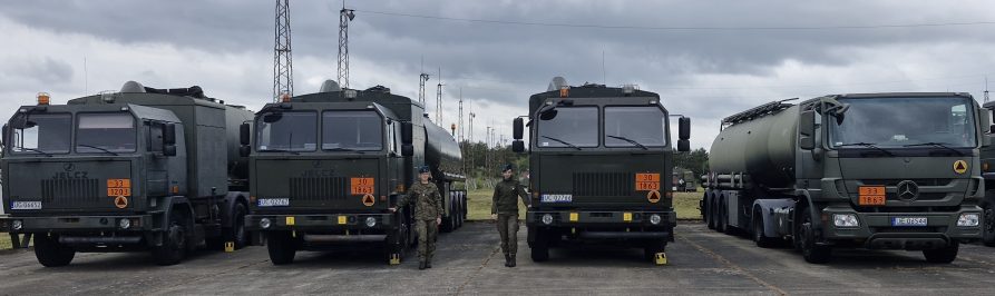 Studentki stojące przy pojazdach transportowo-dystrybucyjnych Służby Materiałów Pędnych i Smarów