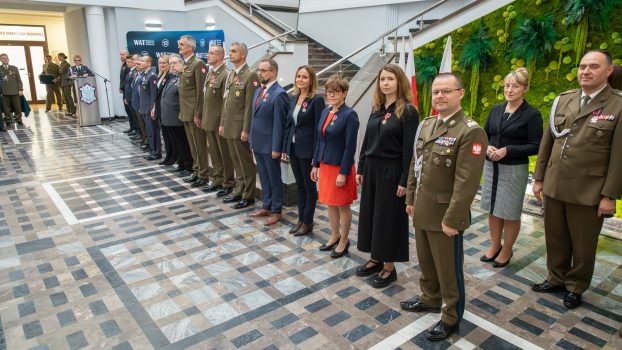 Grupa odznaczonych osób stoi w szeregu.