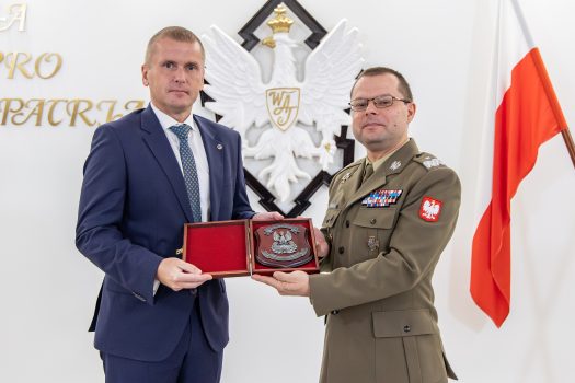 Rektor-Komendant WAT oraz Prezes firmy Milrem Robotics pozują do zdjęcia wspólnie trzymając w rękach okolicznościowym upominek.