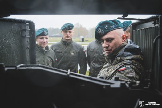 Podchorążowie stoją przy agregacie pompowym na dworzu.