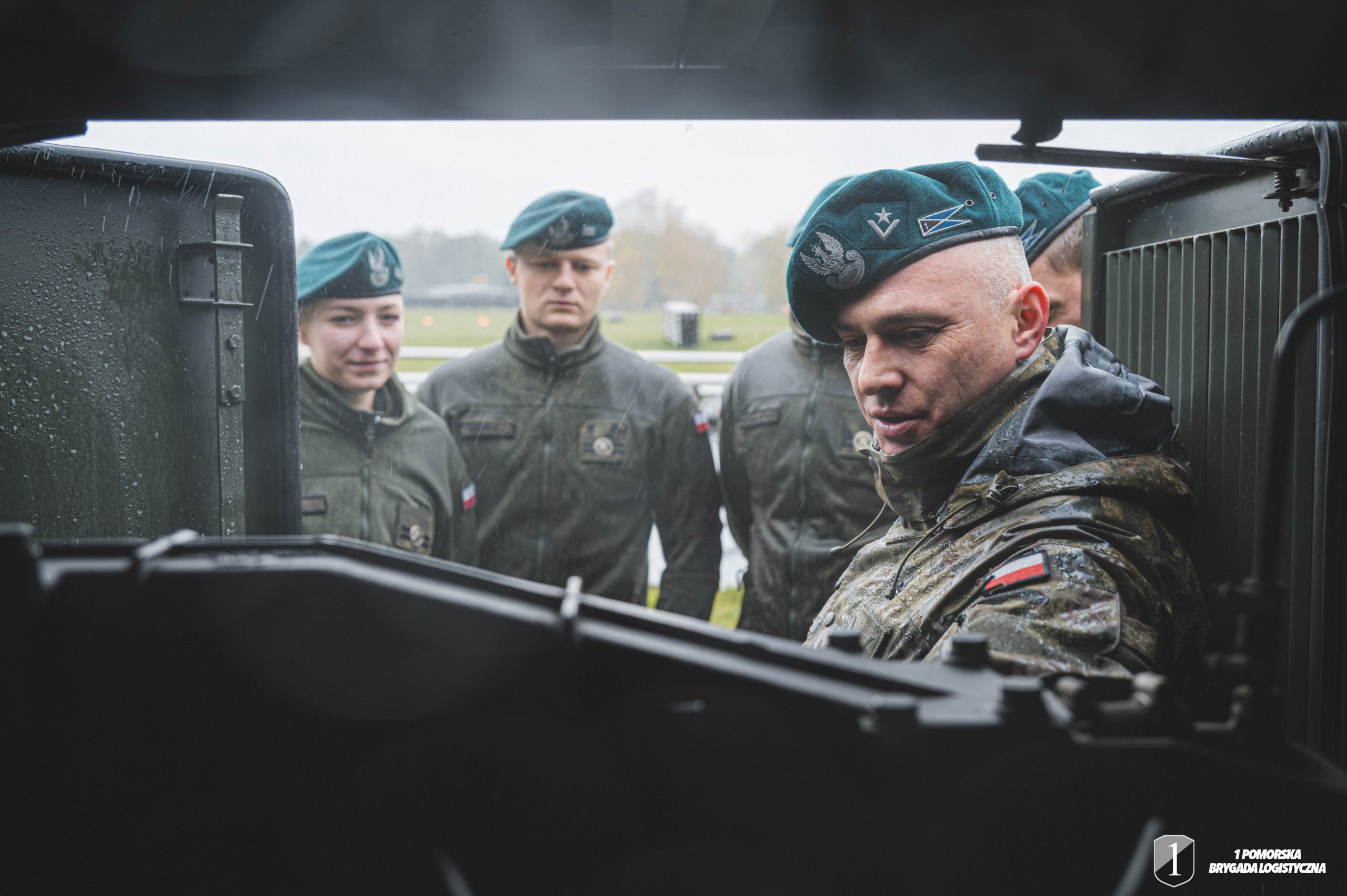 Podchorążowie stoją przy agregacie pompowym na dworzu.