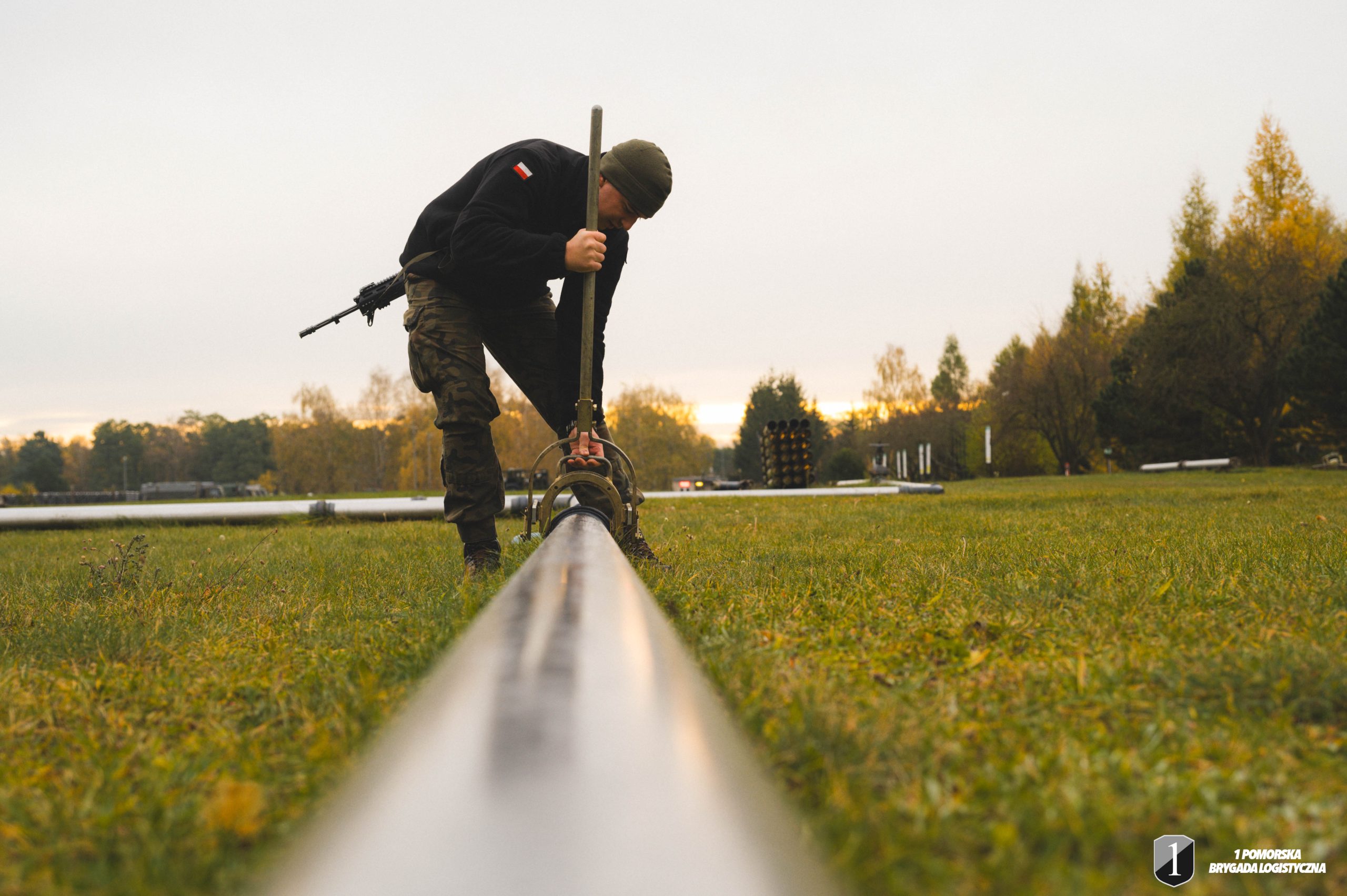 Jeden podchorąży łączy elementy rurociągu polowego.