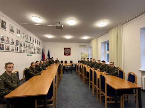 Nagrodzeni podchorążowie z Dziekanem WIM. Studenci siedzą w sali dyscypliny WIM.