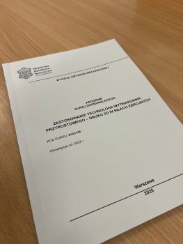 Książka leżąca na biurku - Program Kursu. Na górze na okładce logo WAT.