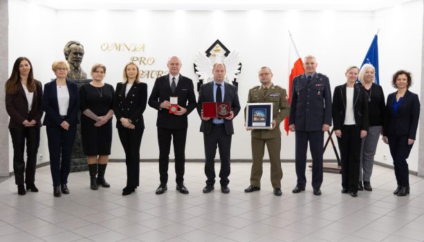 Grupa osób biorących udział w spotkaniu pozująca do zdjęcia. Kady stoi obok siebie.