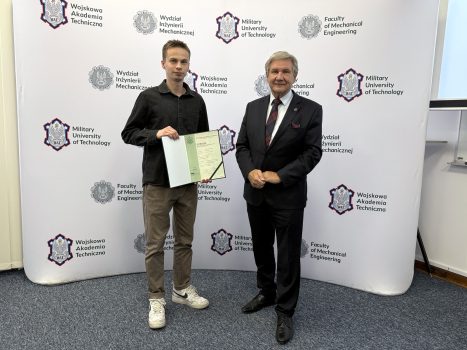 Dziekan wraz ze studentem trzymającym dyplom, w tle ścianka z logami WAT i WIM