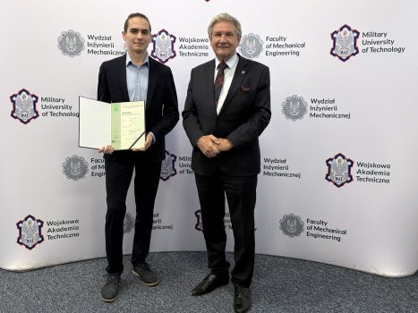 Dziekan wraz ze studentem trzymającym dyplom, w tle ścianka z logami WAT i WIM