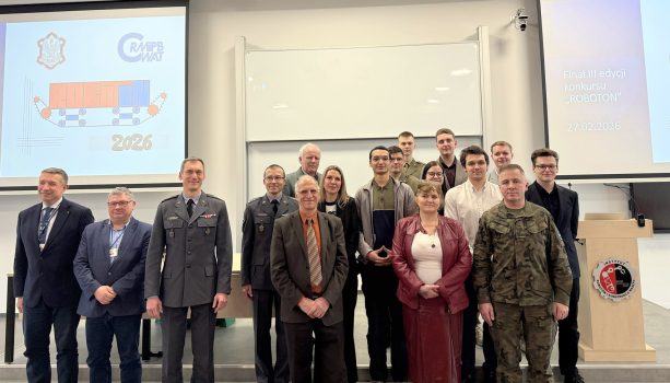 Grupa osób - organizatorów i uczestników ROBOTON pozująca do zdjęcia w auli budynku IRiKM 54a.