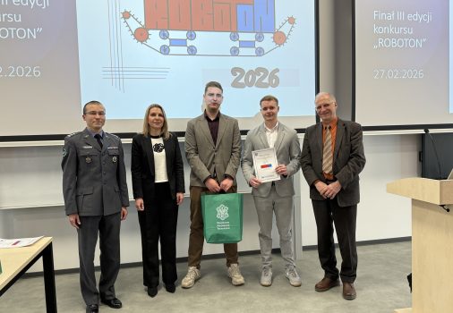 Na tle baneru ROBOTON stoją: sekretarz komisji konkursowej, przedstawicielka Prorektor ds. Studenckich, dwóch studentów – laureatów nagrody Prorektor ds. Studenckich – oraz kierownik IRiKM WIM WAT. Jeden student trzyma dyplom, drugi zieloną torbę prezentową.