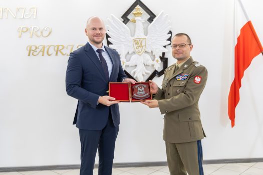 Gen. Przemysław Wachulak, Rektor-Komendant WAT wręcza Panu Mateuszowi Cieplińskiemu, Prezesowi Zarządu Macro System pamiątkowy ryngraf.