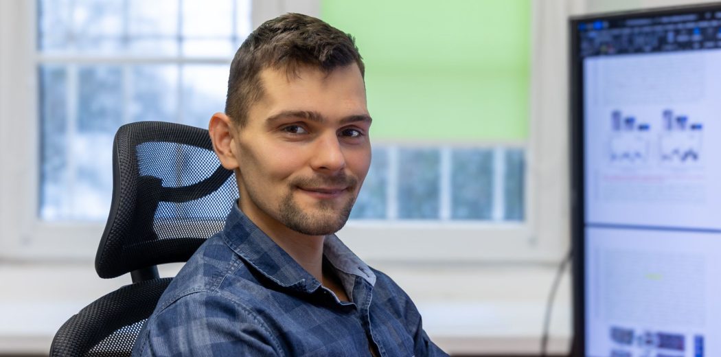 Dr inż. Michał Kucewicz siedzący na fotelu przed komputerem.