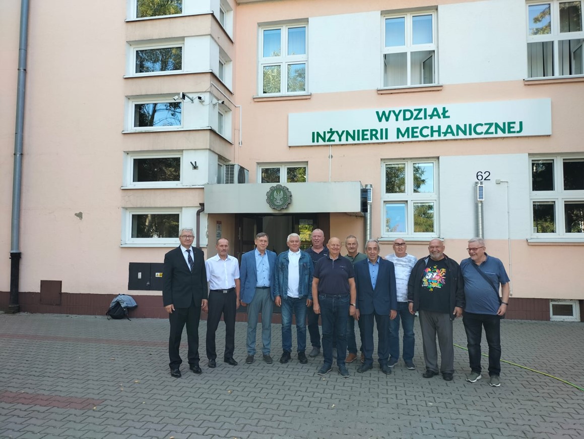 Fot. 3. Goście - Absolwenci stoją tyłem do budynku głównego Wydziału pozując do zdjęcia.