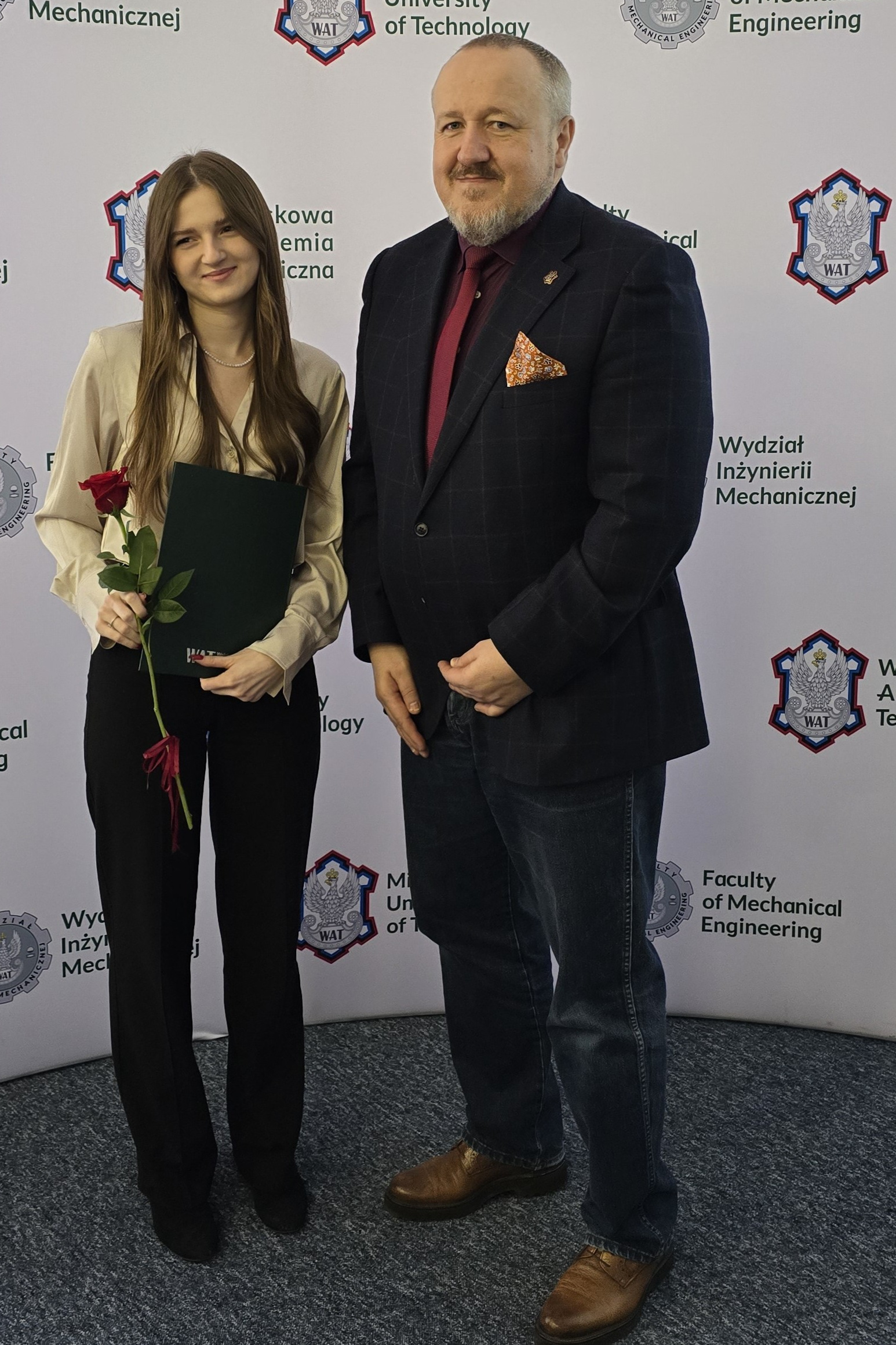 Fot. 1. Izabela Zaraś i dziekan Jerzy Małachowski na tle ścianki wydziałowej z logiem WIM WAT.