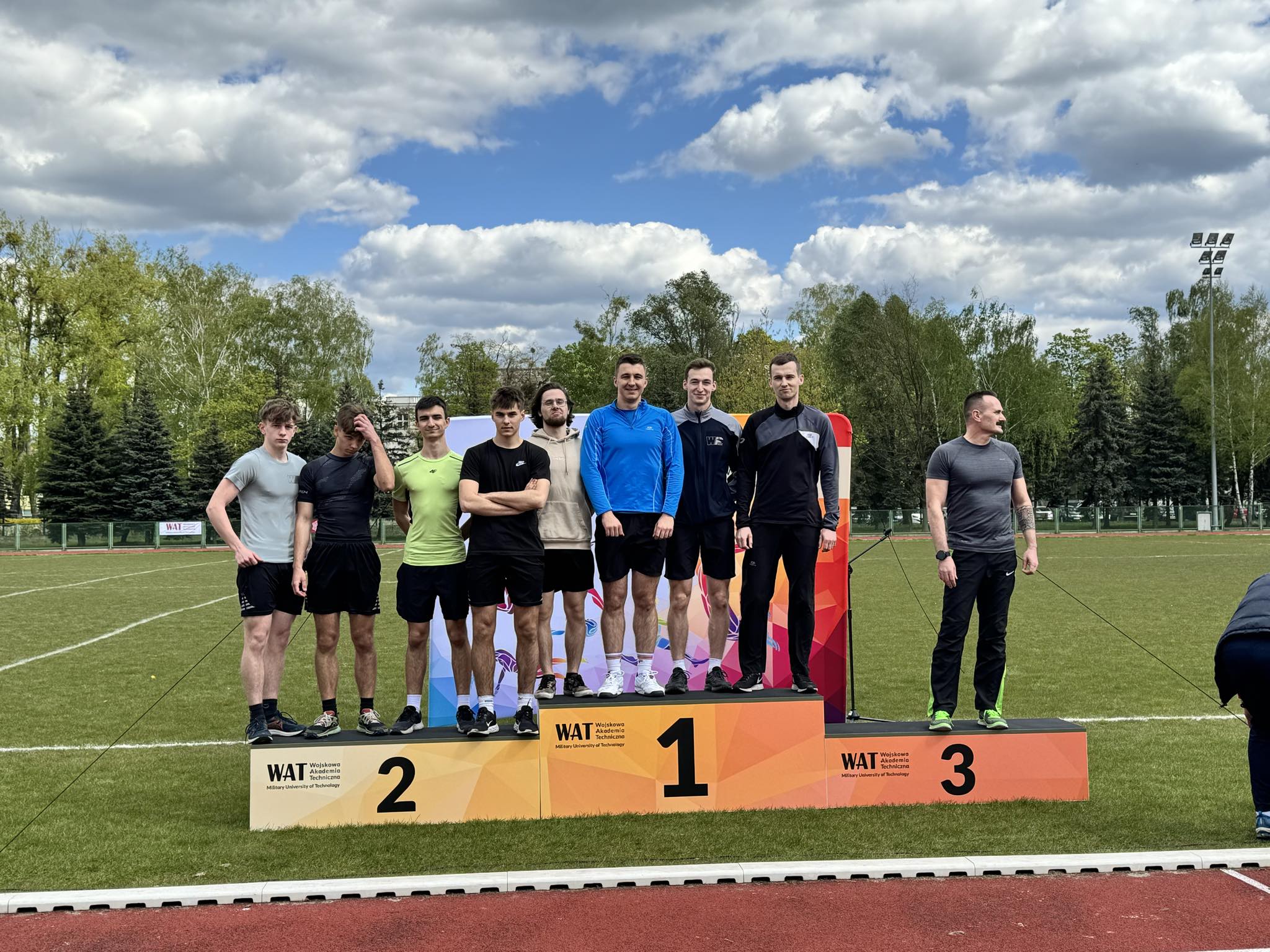 Reprezentanci - sportowcy WIM stoją na wszystkich szczebach podpim pozując do pamiątkowego zdjęcia.