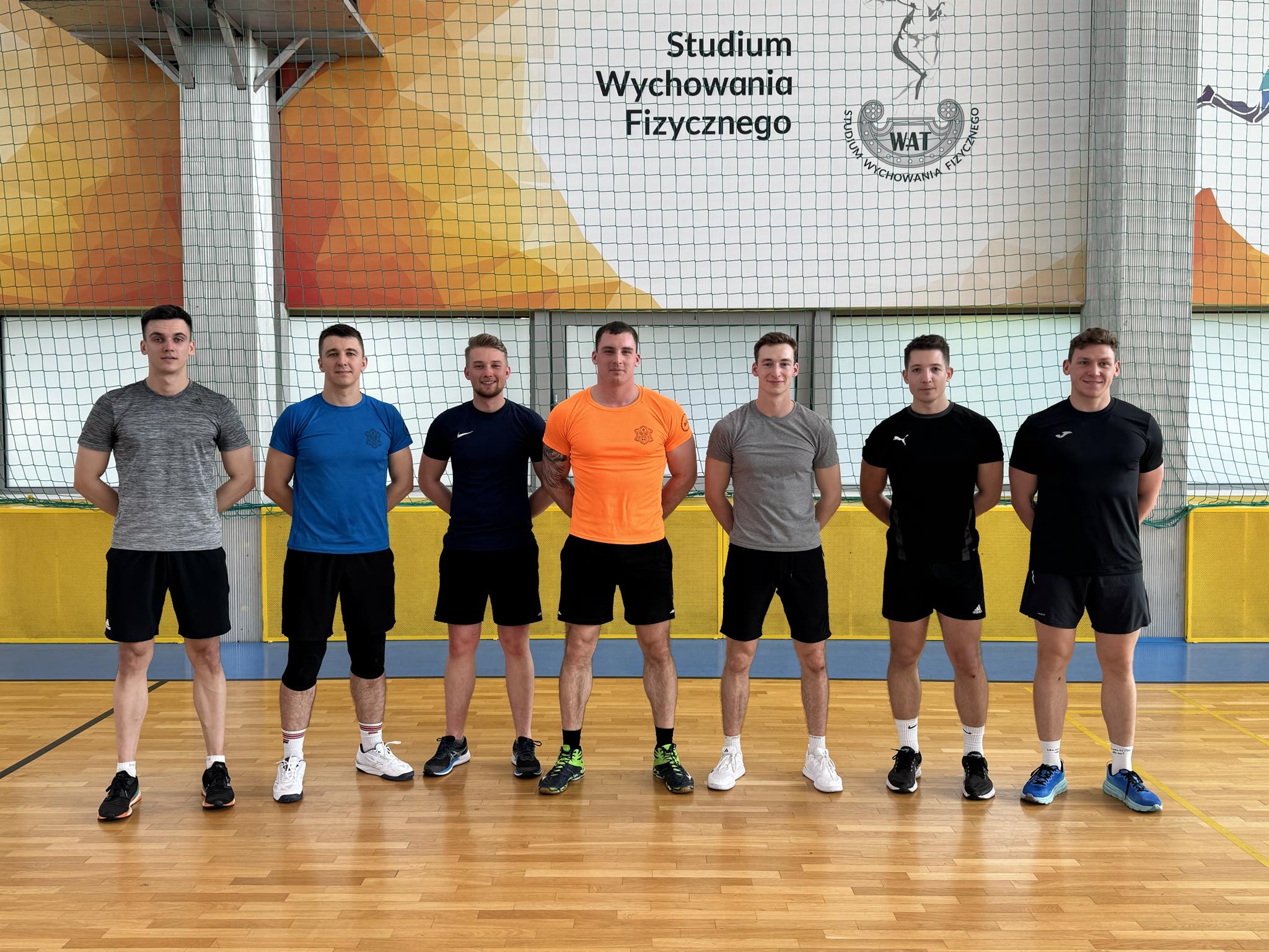 Reprezentanci - sportowcy WIM pozują do pamiątkowego zdjęcia na sali sportowej.