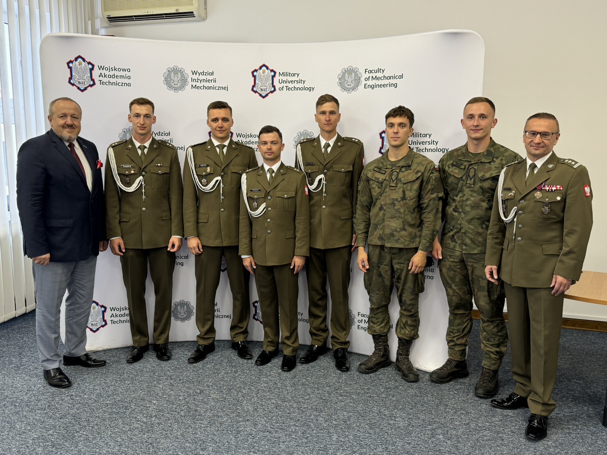 Wyróżnieni absolwenci studiów wojskowych na kierunku mechanika i budowa maszyn. Studenci, Dziekan i Zastępca Dziekana stoją w sali Rady Wydziału na tle ścianki z logami WIM i WAT.