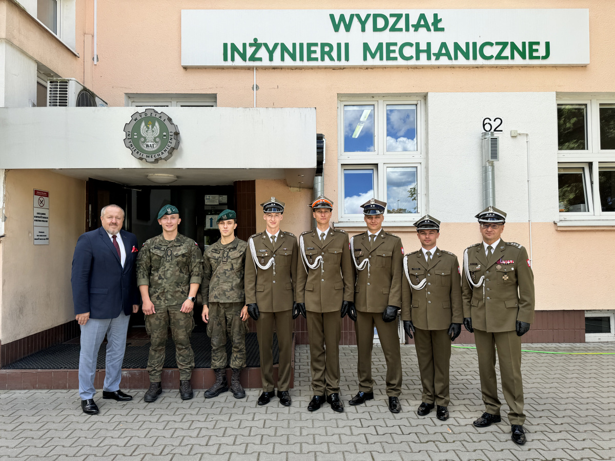 Wyróżnieni absolwenci studiów wojskowych na kierunku mechanika i budowa maszyn wraz z Dziekanem i Zastępcą Dziekana stoją przed budynkiem WIM. Na górze baner z nazwą Wydziału oraz logiem WIM.