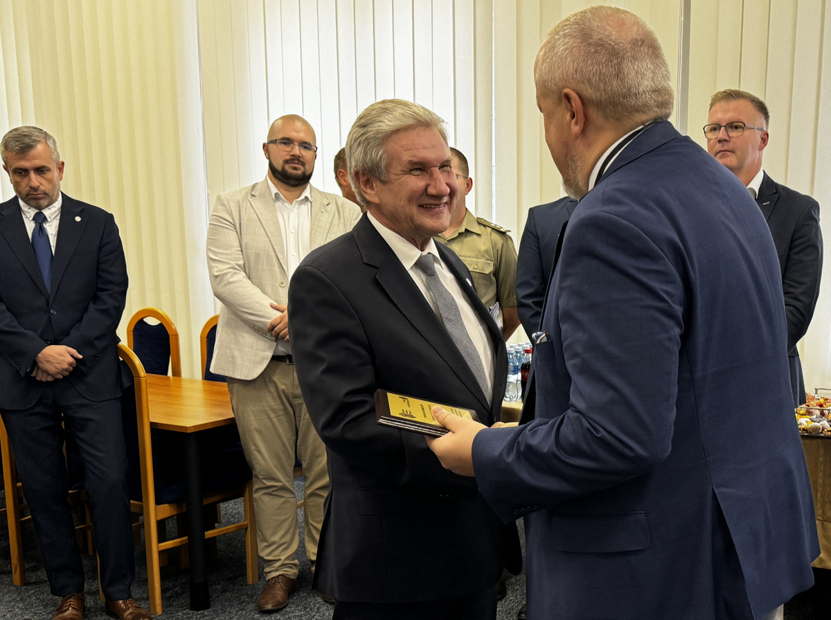 Dziekan J.Małachowski dziękuje i wręcza pamiątkowy ryngraf prof. J.Jackowskiemu, w tle kilka osób, z tyłu baner WIM WAT.