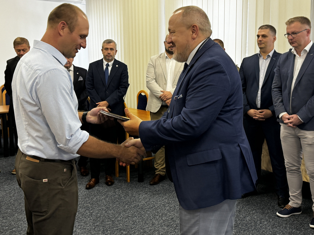 Dziekan J.Małachowski dziękuje i wręcza pamiątkowy ryngraf dr. K.Gocmanowi, w tle kilka osób, z tyłu baner WIM WAT.