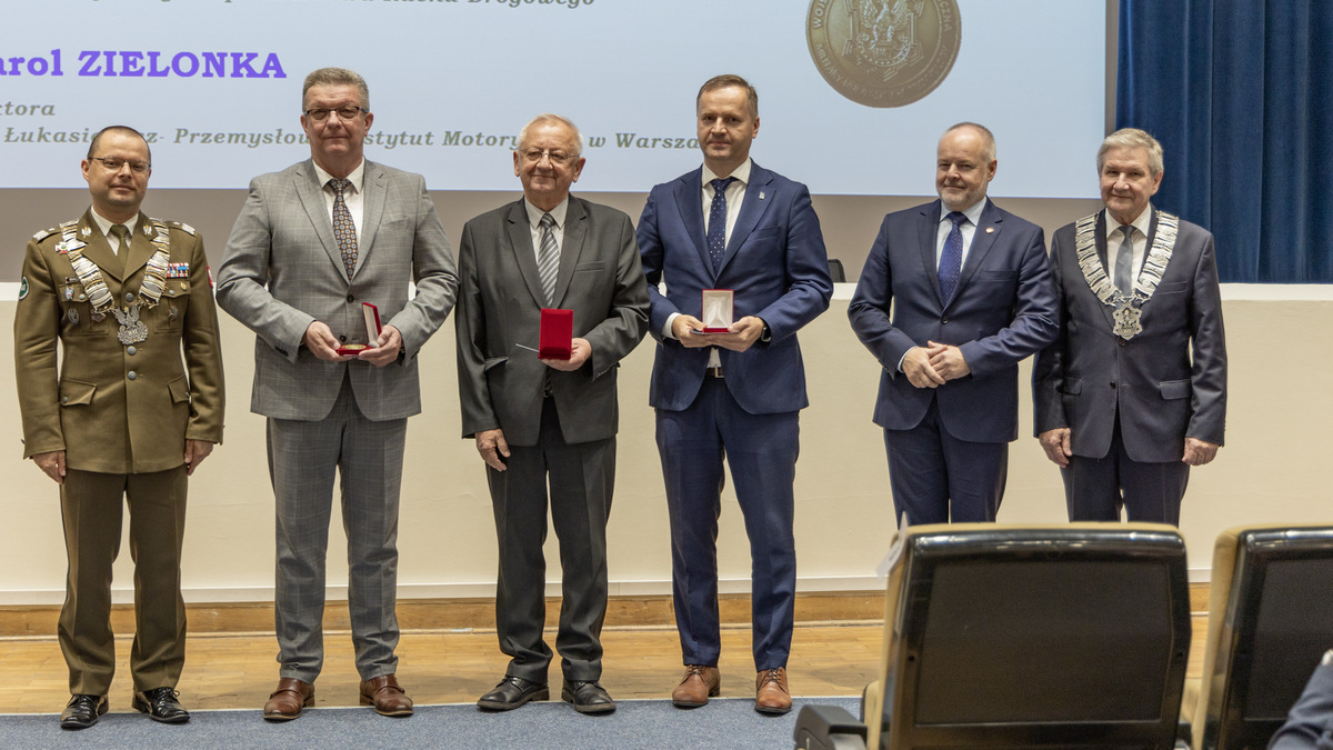 Tyłem do sceny, przodem do zgromadzonych stoją wyróżnione osoby.