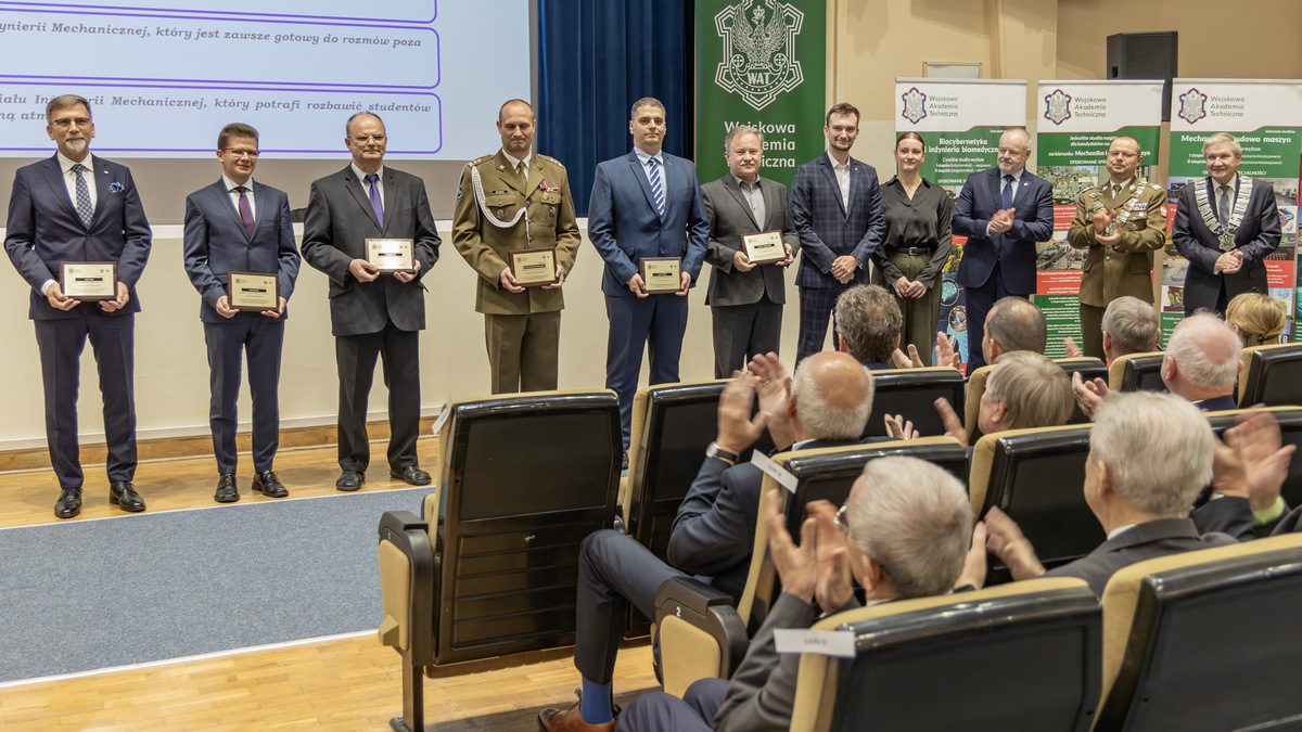 Tyłem do sceny, przodem do zgromadzonych stoją wyróżnione osoby.