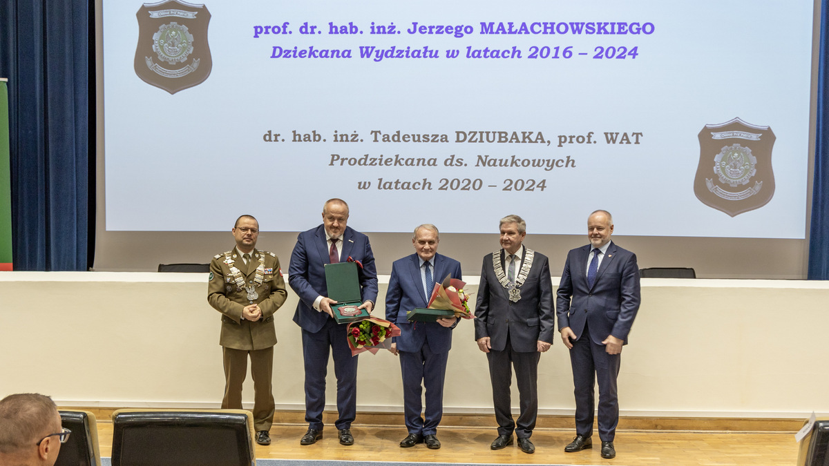 Tyłem do sceny, przodem do zgromadzonych stoją wyróżnione osoby.