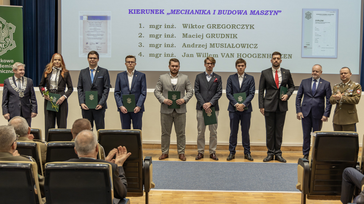 Tyłem do sceny, przodem do zgromadzonych stoją wyróżnione osoby.