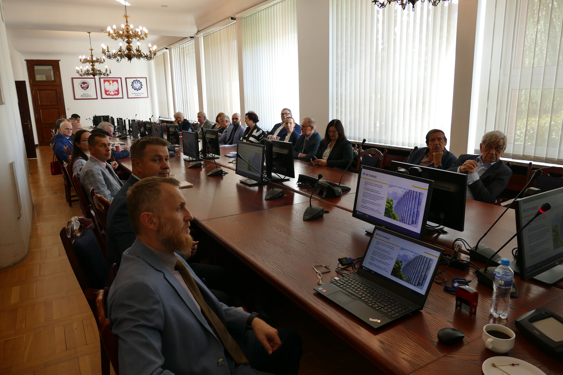 Grupa osób siedząca przy podłużnym stole.