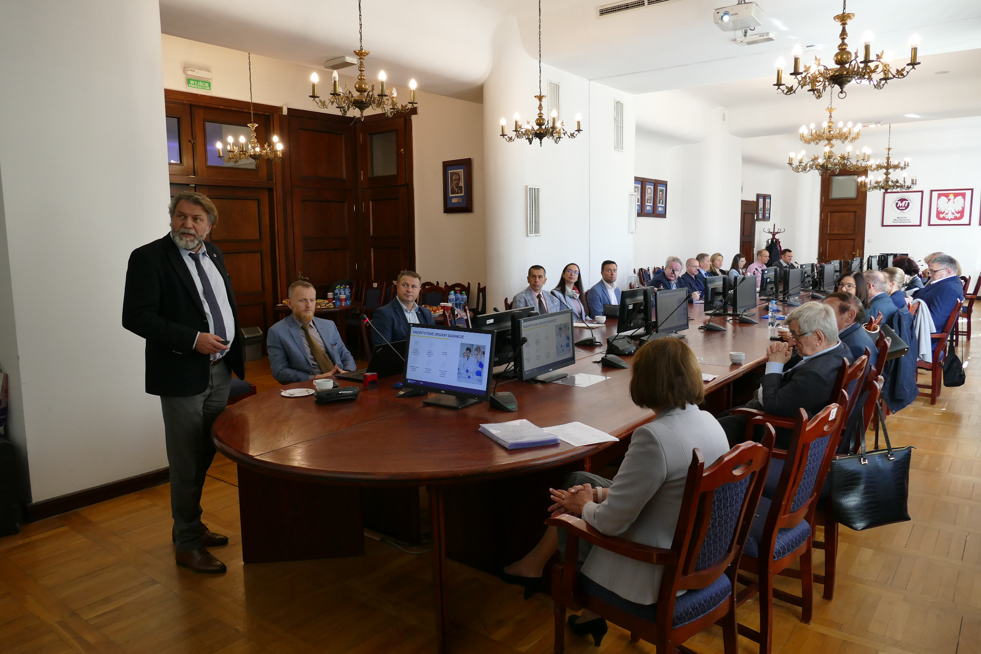 Grupa osób siedząca przy podłużnym stole.