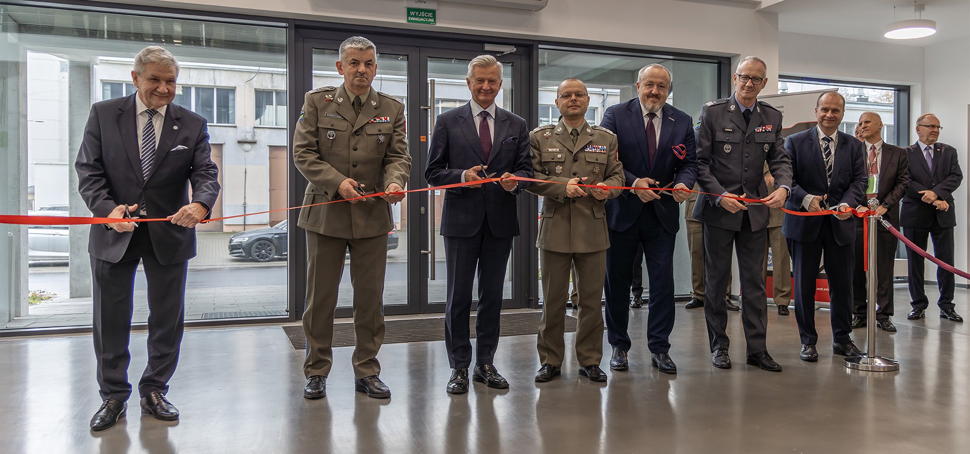 Grupa osób przecina symbolicznie czerwoną wstęgę.