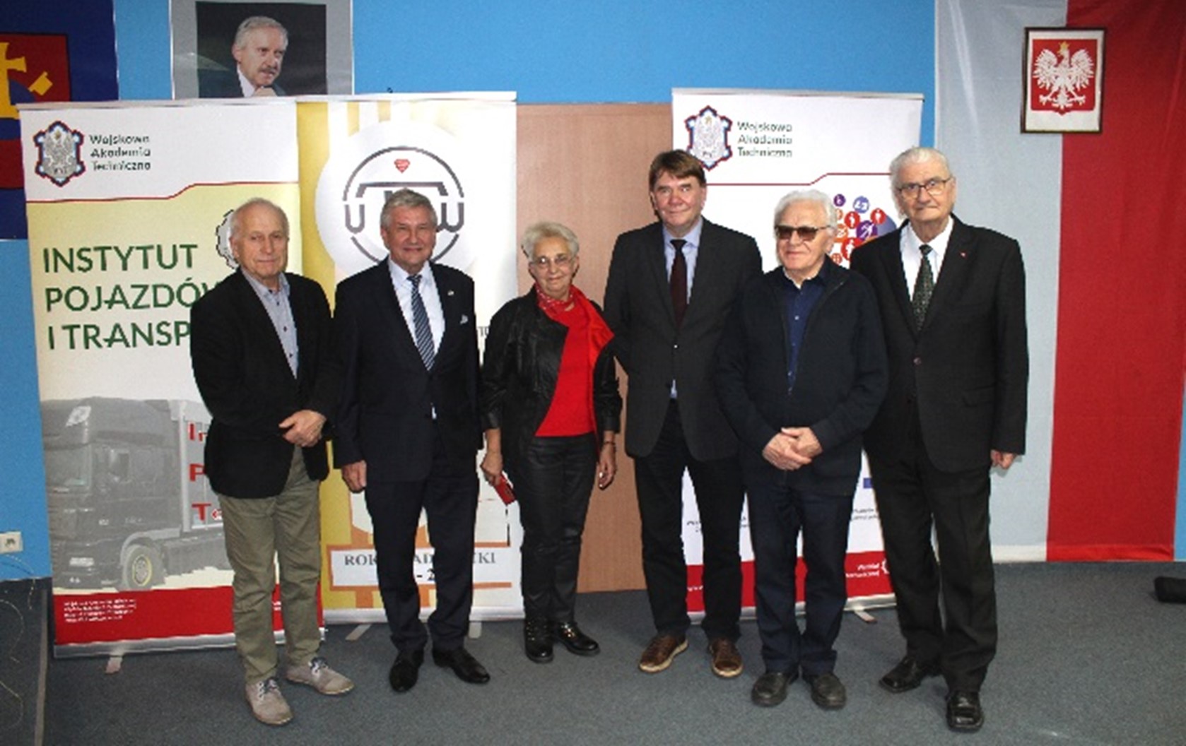 na zdjęciu widoczni przedstawiciele Uniwersytetu Trzeciego Wieku w Ostrowie Wielkopolskim oraz delegacja z Wydziału Inżynierii Mechanicznej WAT. W tle banery Wydziału Inżynierii Mechanicznej WAT.