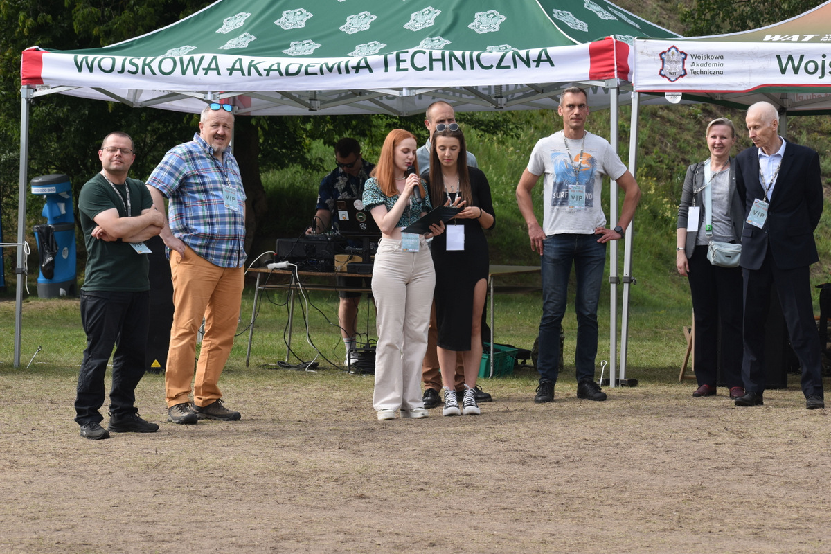 Piknik WIM i WML - na zdjęciu osoby stoją na polanie, na trawie, w tle namioty z napisami WAT.