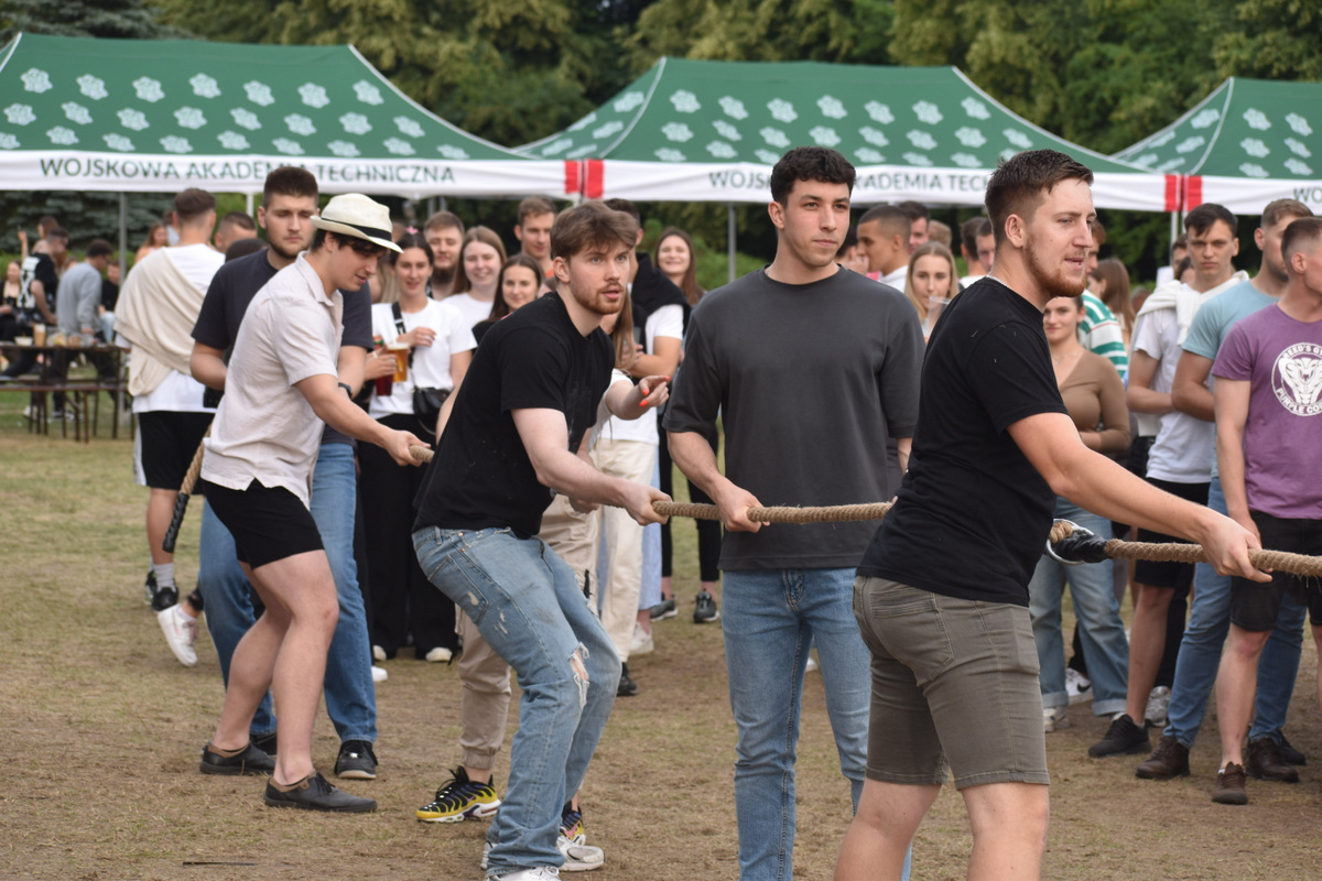 Piknik WIM i WML - na zdjęciu osoby stoją na polanie, na trawie, w tle namioty z napisami WAT.